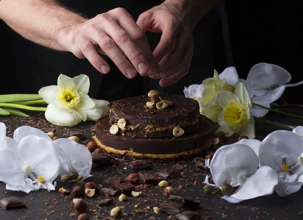 Chef is decorating little chocolate cake with nuts. Stock Image