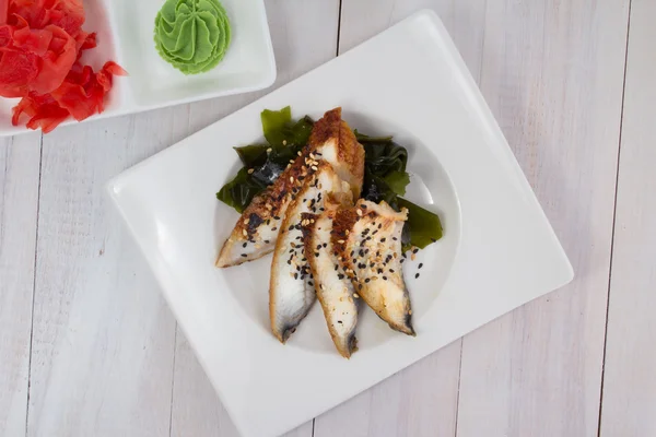 Anguila sashimi con jengibre y wasabi sobre un plato blanco sobre fondo de madera —  Fotos de Stock