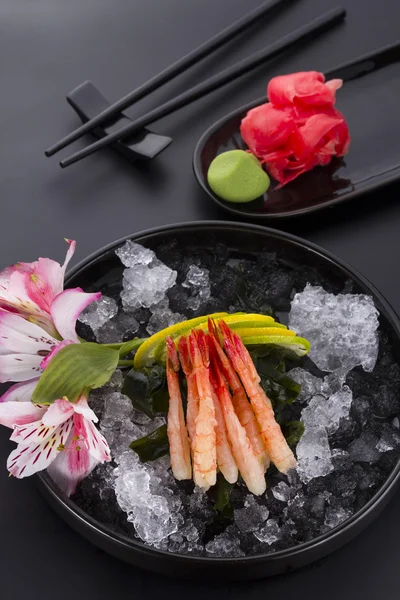 Japanische Küche, Shrimp Sashimi mit Eis mit Ingwer und Wasabi auf einem schwarzen Teller — Stockfoto