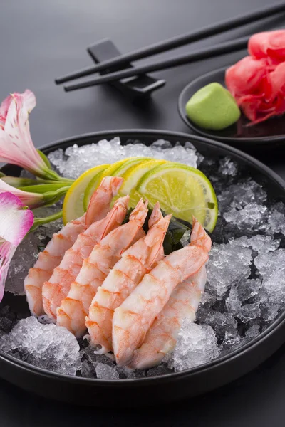 Japonská kuchyně, krevety Sashimi s ledem s wasabi na černém plátu a zázvorem — Stock fotografie