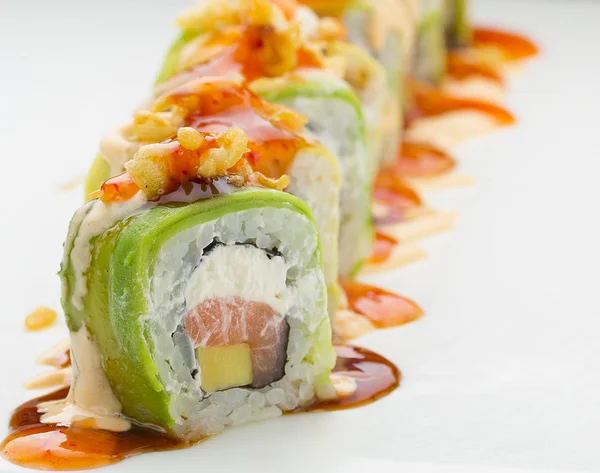 Sushi con salmón de aguacate y queso. Crunch Roll. Con deliciosas salsas. En un plato sobre fondo blanco . — Foto de Stock