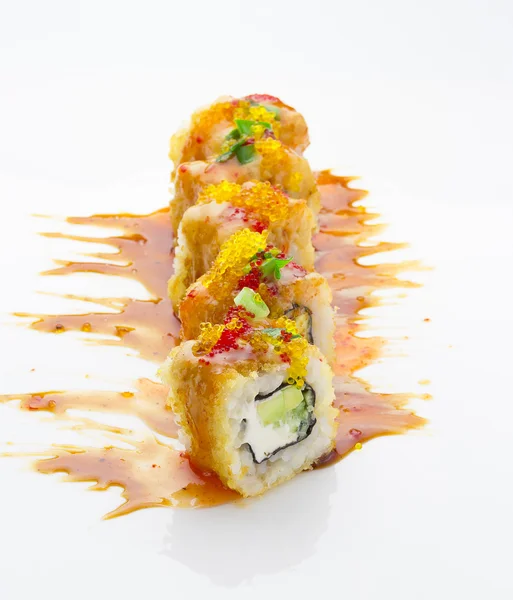 Rolo de sushi crocante com queijo e abacate decorado com cebola verde e molhos de especiarias sobre fundo branco — Fotografia de Stock