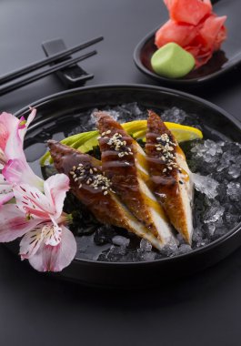 Yılan balığı sashimi buzlu zencefil wasabi siyah arka plan üzerinde siyah bir plaka üzerinde
