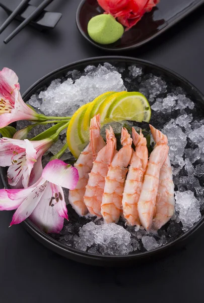 Cucina giapponese, gamberetti Sashimi con ghiaccio con zenzero e wasabi su un piatto nero — Foto Stock