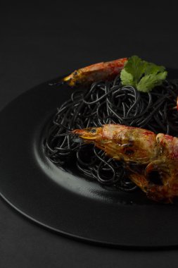 Karidesli koyu arka plan üzerinde siyah spagetti (noodle)