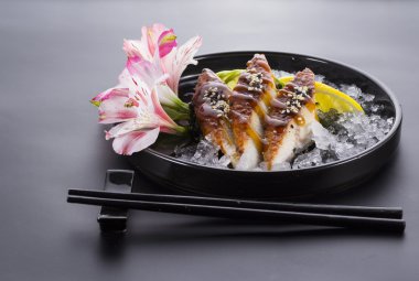 Yılan balığı sashimi buzlu zencefil wasabi siyah arka plan üzerinde siyah bir plaka üzerinde