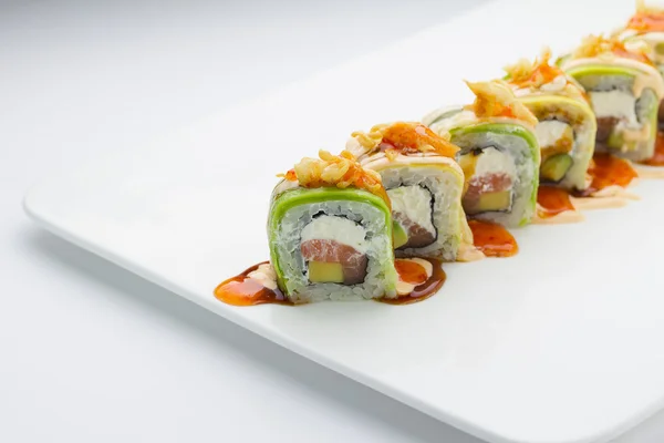 Sushi met zalm avocado en kaas. Crunch Roll. Met heerlijke sauzen. Op een plaat op witte achtergrond. — Stockfoto