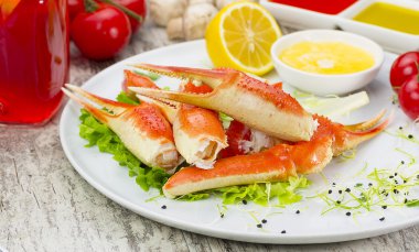 Haşlama yengeç pençeleri ahşap arka plan üzerine sosunu, limon ve kiraz domates ile