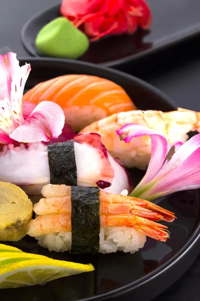 Sushi impostato su una piastra nera e sfondo nero — Foto Stock