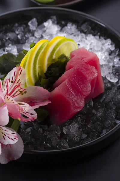 Tonfisk sashimi med is på en svart plåt — Stockfoto