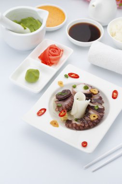 Zencefil wasabi ve soslar ile beyaz tabakta ahtapot salatası.