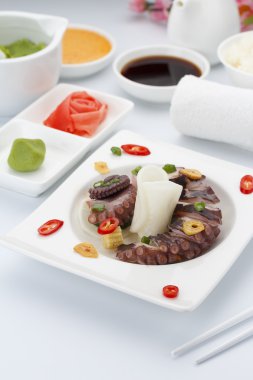 Zencefil wasabi ve soslar ile beyaz tabakta ahtapot salatası.