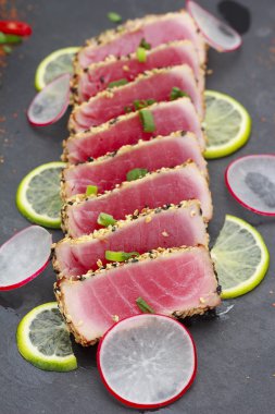 Ton balığı filetosu susam ile dekore edilmiş limon ve sebze ile