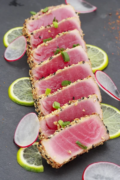 Filé de atum com gergelim decorado com limão e legumes — Fotografia de Stock