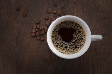 Kahve fincanı. Kahve çekirdekleri ve ahşap bir masa çikolata