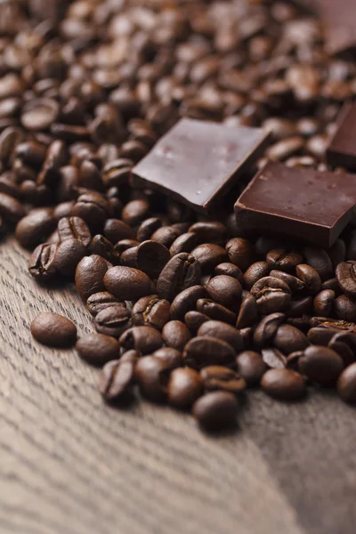 Кофейные зерна с шоколадом на деревянном фоне — стоковое фото