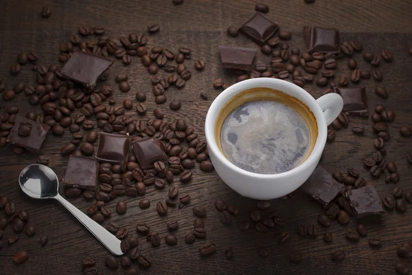 Šálek kávy. Zrnková káva a čokoláda na dřevěný stůl — Stock fotografie