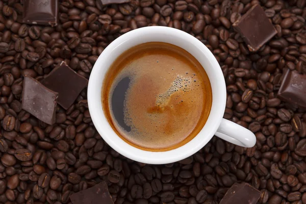 Šálek kávy. Zrnková káva a čokoláda na dřevěný stůl — Stock fotografie