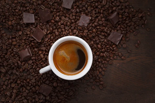 Uma chávena. Grãos de café e chocolate em uma mesa de madeira — Fotografia de Stock