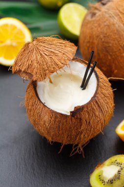 Hindistan cevizi kivi, portakal ve limon ile siyah bir tabloda kokteyl.