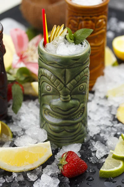 Tropische Cocktails, serviert in einem Glas im Tiki-Stil und garniert mit Früchten und Eis — Stockfoto