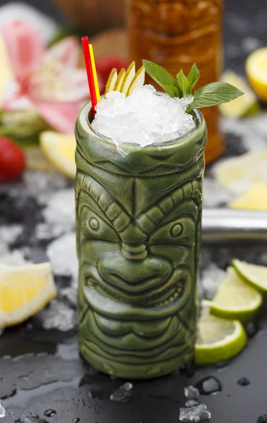 Tropische cocktails geserveerd in een glas tiki stijl en gegarneerd met fruit en ijs — Stockfoto