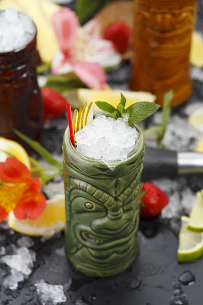 Tropische cocktails geserveerd in een glas tiki stijl en gegarneerd met fruit en ijs — Stockfoto