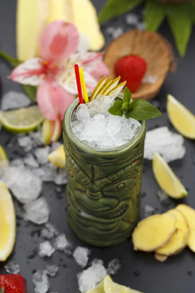 Τροπικά κοκτέιλ σερβίρονται σε ποτήρι στυλ tiki και γαρνίρεται με φρούτα και πάγο — Φωτογραφία Αρχείου
