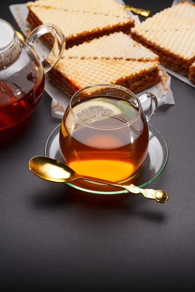 Słodki wafel trójkątne ciastka z kondensowanym mlekiem i świeże gorącej herbaty czarne na czarnym stole — Zdjęcie stockowe