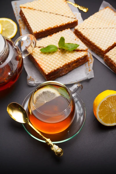 練乳と黒いテーブルに新鮮な熱い紅茶と甘いワッフル三角ケーキ — ストック写真