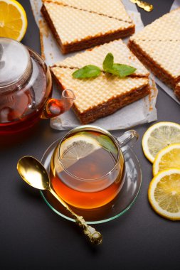 Yoğunlaştırılmış süt ve taze sıcak siyah çay siyah bir tablo ile tatlı waffle üçgen kek