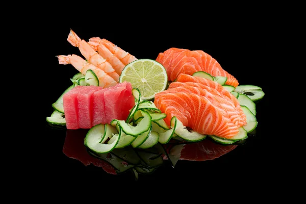 Sashimi beállítása (garnéla, lazac, tonhal) mész és uborka fekete háttér. — Stock Fotó