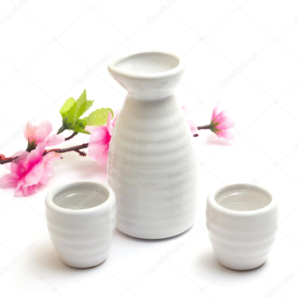Japanese traditional sake cups and bottle with sakura , sake is a japanese liquor made from fermented rice. Isolated on white background.
