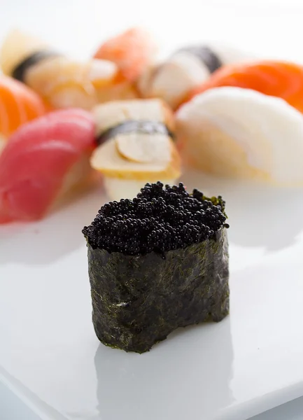 Суши гункан с черным тобико и нигири на белой тарелке — стоковое фото