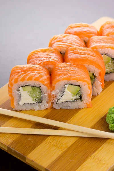 Rolo de sushi de salmão em uma chapa de madeira — Fotografia de Stock