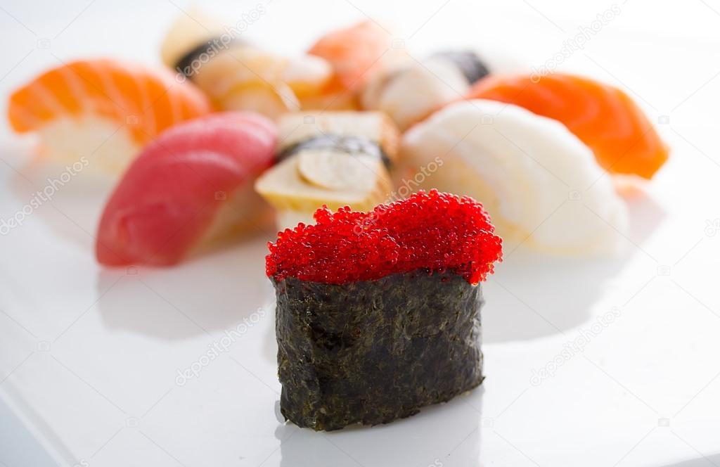 Sushi gunkan with black tobiko and nigiri on a white plate