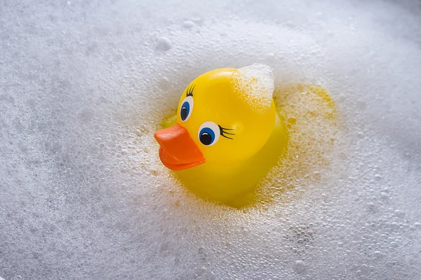 Yellow rubber duck floating in soap suds — Stock Photo, Image