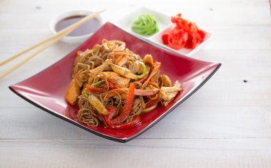 Soba noodle ile deniz ürünleri ve ahşap arka plan üzerinde tatlı ve ekşi soslu sebze