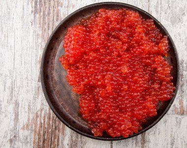 Vintage bir arka plan üzerinde siyah bir tabak içinde kırmızı havyar