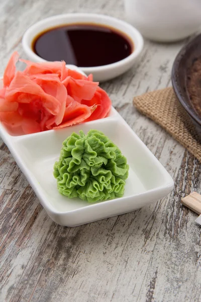 Condiments traditionnels japonais - wasabi, gingembre et sauce soja sur fond de bois — Photo