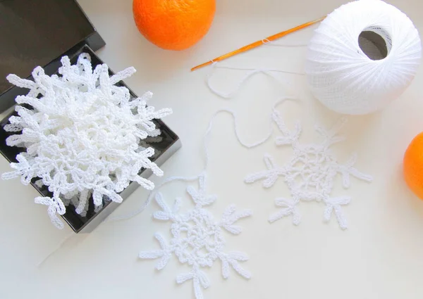 White snowflakes are crocheted of cotton yarn to decorate the Christmas tree and interior for Christmas.