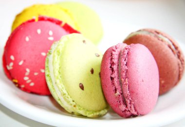 Fransız kurabiyeleri, küçük yuvarlak renkli kurabiyeler ve bir fincan sıcak çay.