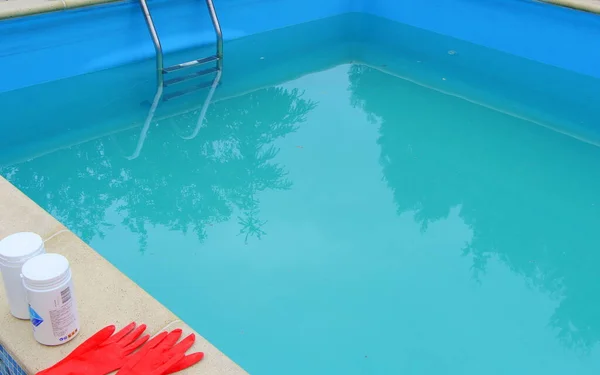 スイミングプールの消毒のためのスタッフの手の中に塩素の白いミニタブレット 水泳シーズンの始まりは暑い夏です ゴム保護赤い手袋 水浄化 — ストック写真