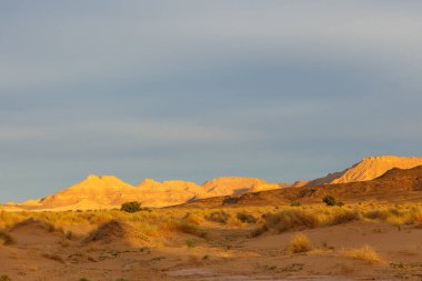 Sahra Çölü 'nde gün batımı. Batan güneşin ışınlarındaki dağlar. Fas