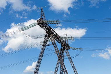 Yüksek voltajlı güç iletim kulesi. Mavi gökyüzüne karşı elektrik yalıtıcıları.