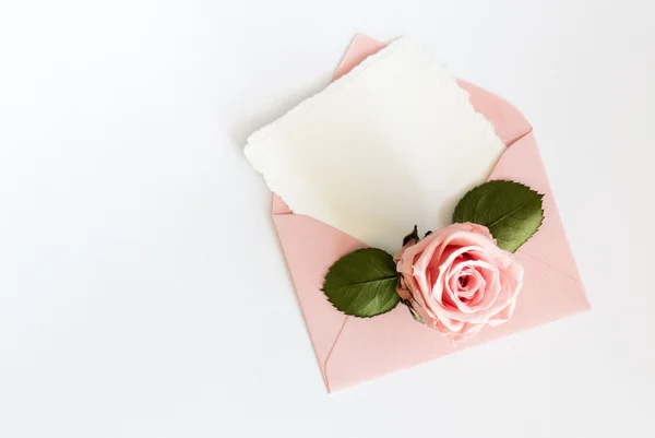 Pink envelop with white card and rose. Flat lay. — Stock Photo, Image