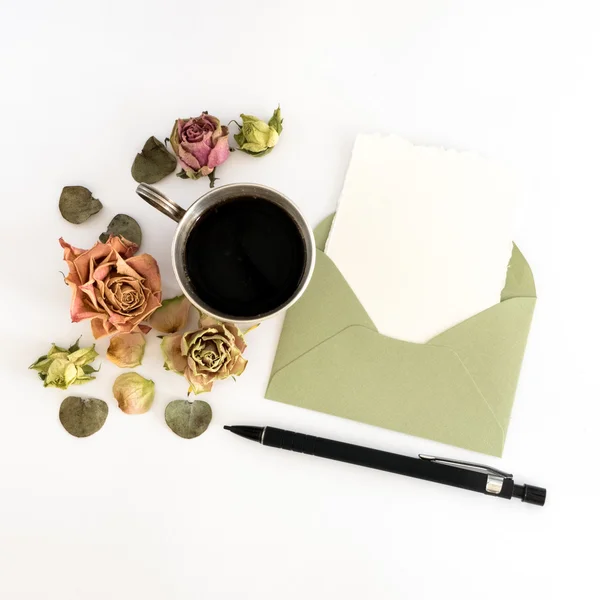 Ceașcă de cafea, hârtie albă în plic, stilou și flori. plat, vedere de sus — Fotografie, imagine de stoc