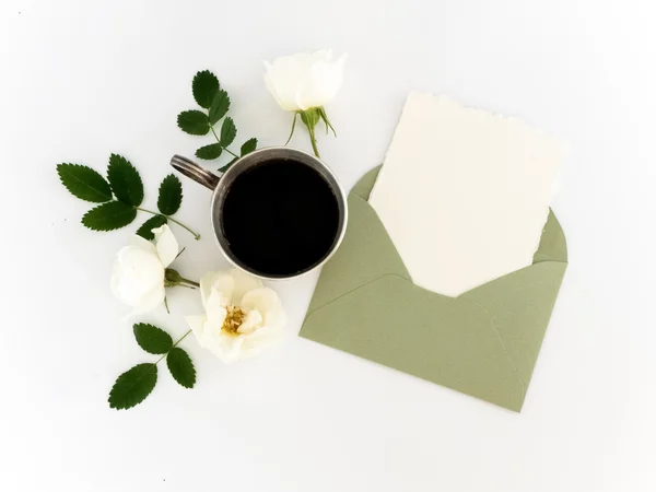 Tasse de café, papier blanc dans l'enveloppe, stylo et fleurs. plan plat, vue sur le dessus — Photo