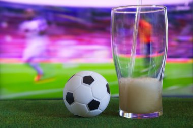 Bardak bira ve tv, futbol maçı arka planda