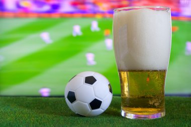 Bardak bira ve tv, futbol maçı arka planda